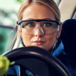 A driver wearing ANSI-certified safety glasses behind the wheel in daylight