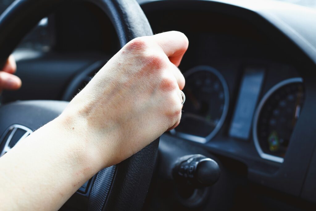 A driver with both hands on the wheel, clear highway, seatbelt visible promoting safe driving habits
